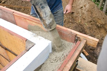 Construction worker pouring concrete in wall mold
