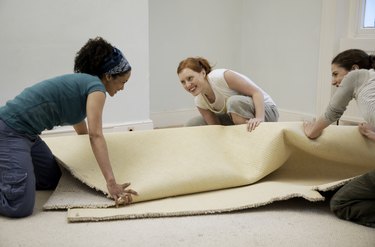 Friends rolling up an old carpet