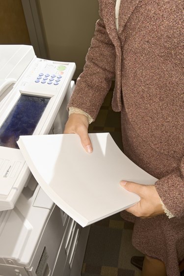 Woman holding paper next to copy machine