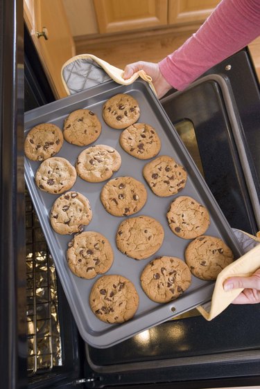 Woman removing cookies from oven