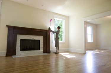 Woman placing orchid on fireplace in empty room