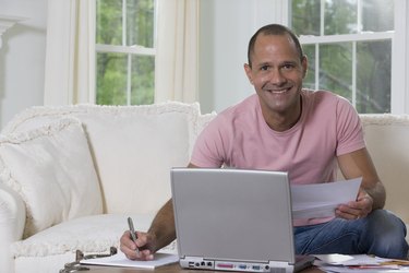 Hispanic man sorting out bills in front of a laptop