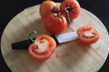 Ceramic knife and red tomatoes on cutting board