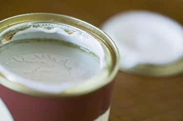Pot of green paint, open, lid near by, close up