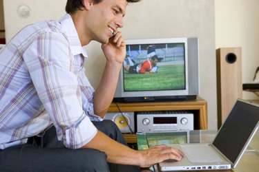 Man using cellular phone while on laptop