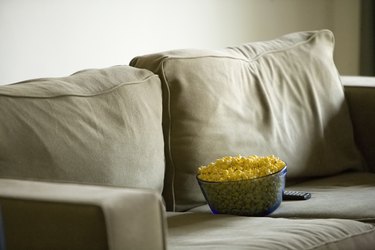 Bowl of popcorn and remote control on sofa