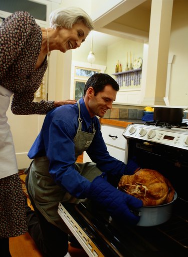 Man and Woman Putting a Turkey in the Stove