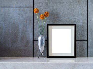 Modern interior wall with flowers vase and blank picture frame