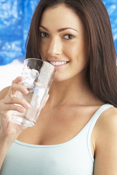 Young Woman Drinking Glass Of Water In Studio