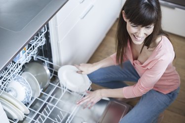 middle aged girl in the kitchen using dishwasher
