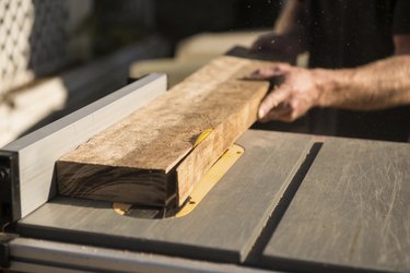 man cutting a thin strip of wood on a table saw