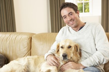 Young man with dog sitting on sofa