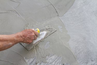 Hand using trowel on fresh concrete in construction site