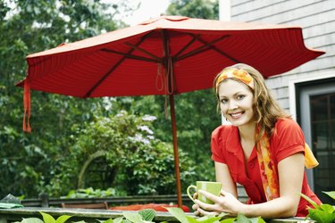 Smiling woman with coffee by patio umbrella