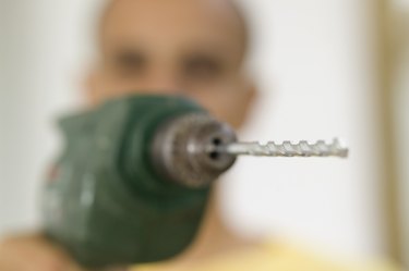 Close-up of the tip of a drill bit of an electric drill held by a man