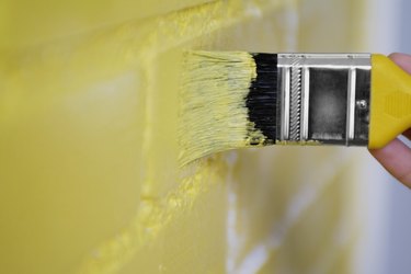 Person painting the wall yellow