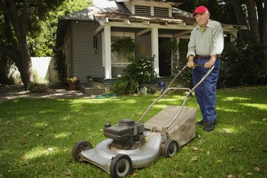 Portrait of elderly man mowing lawn