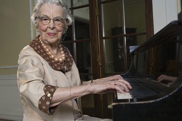 Senior woman playing piano, smiling, portrait