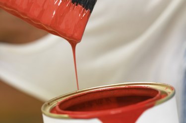 Paint dripping from a paint brush into a paint can