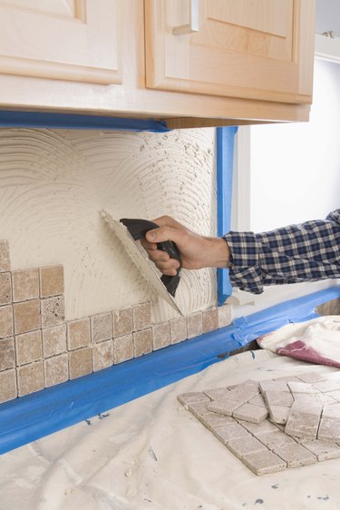 Person putting grout on wall with trowel