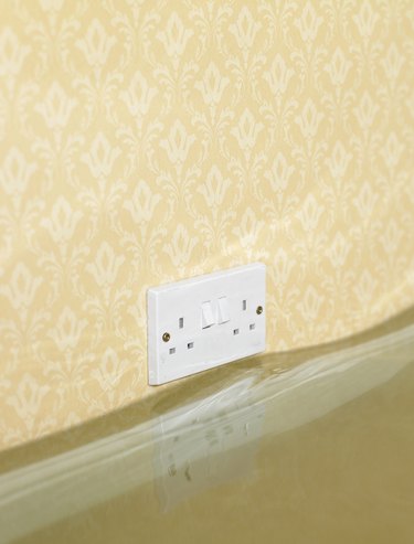Electric wall outlet reflected in water in flooded living room