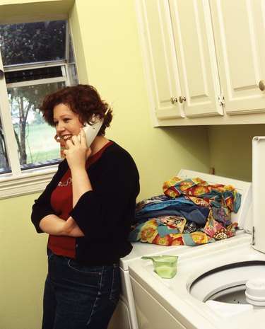 Woman talking on telephone in laundry room