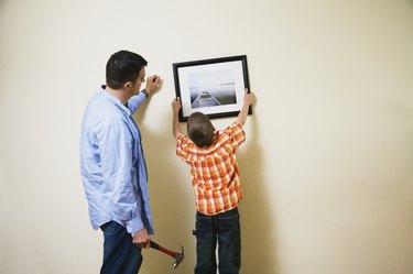 Father and son hanging picture together
