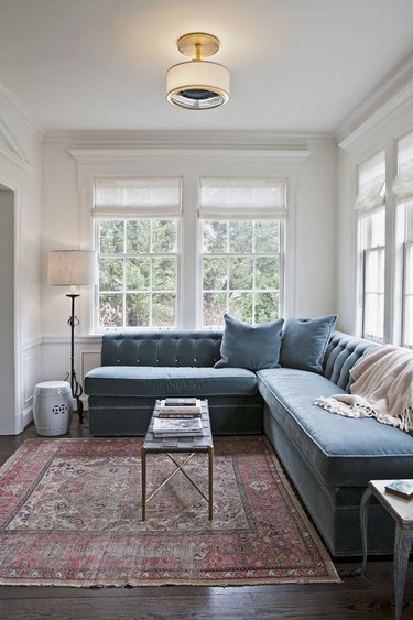 Living room with large windows, gray couch and a semi flush mount light.
