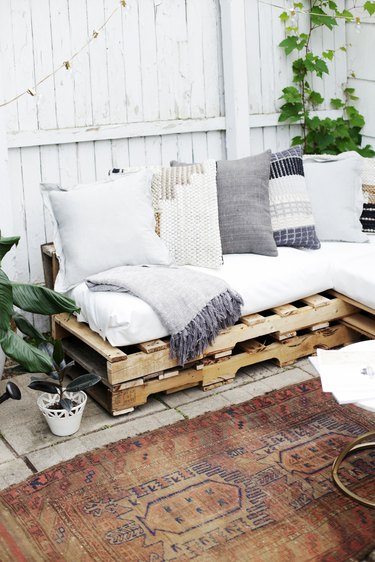 Wood pallet couch on patio with vintage rug.