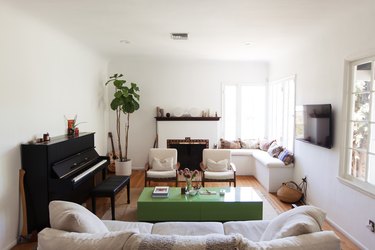 Living room with piano, green coffee table, built-in, and bohemian pillows