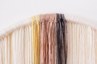 Tying dyed yarn strands onto hula hoop