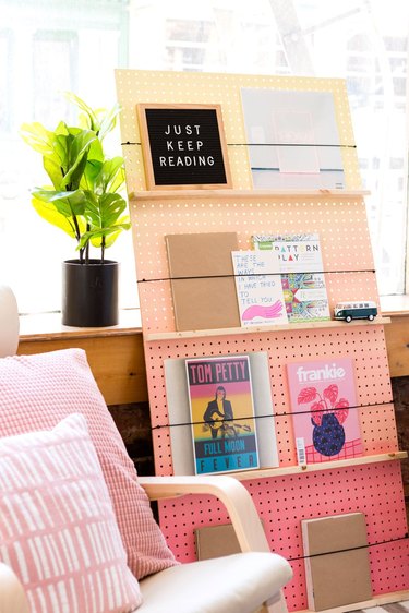 A pegboard bookcase that goes from pink to light orange