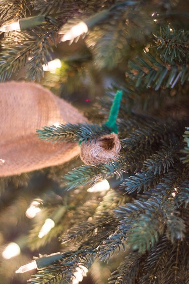 A pipe cleaner secures a ribbon garland to a Christmas tree