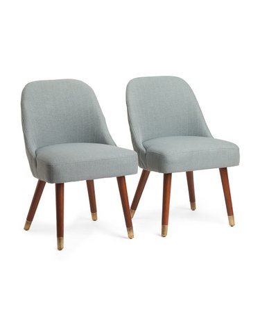 Two wood-legged dining chairs with plain linen upholstery.