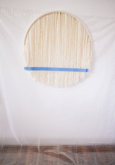 Plastic sheet hung behind hula hoop to protect wall and floor
