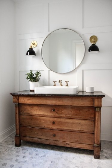 white wall flat panel white wainscoting round mirror and sink vanity