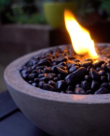 DIY tabletop concrete fire bowl on an outdoor coffee table in the evening.