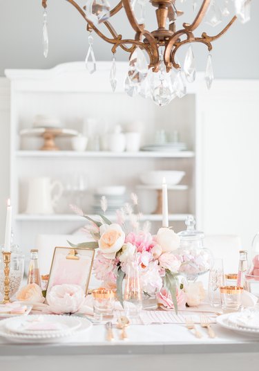 A white table with pale pink flowers and rose god metallic accents.