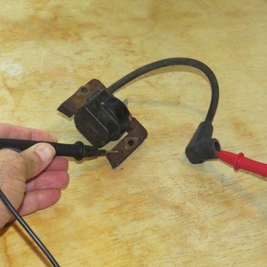 Wire leads testing a lawnmower ignition coil.