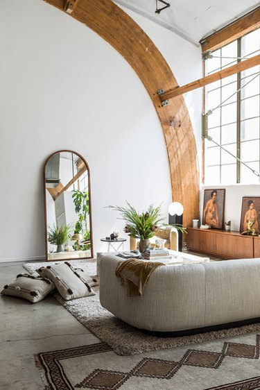 Living room with arched beams and mirror and curved gray couch