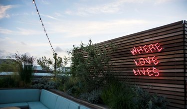 Rooftop bar with "Where Love Lives" neon sign.