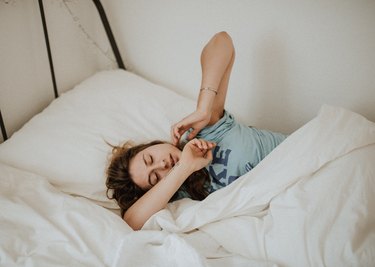 Young woman stretching in bed.