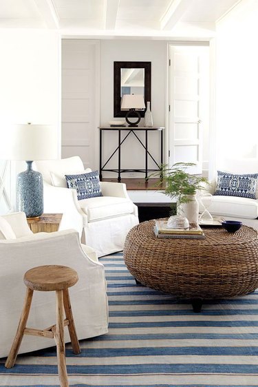 White armchairs circled around roud woven coffee table