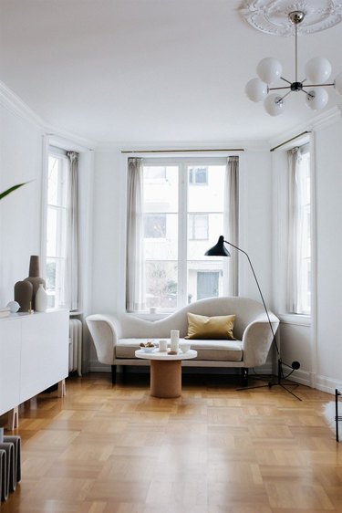 A small minimalist space with dramatic shaped couch and wood floors.