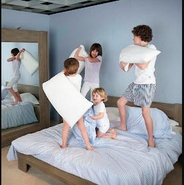 Kids playing on a bed.