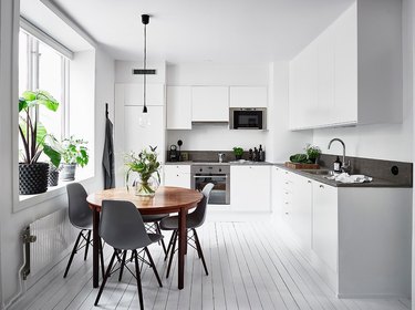 White kitchen with wood circular table and gray mid-century dining chairs
