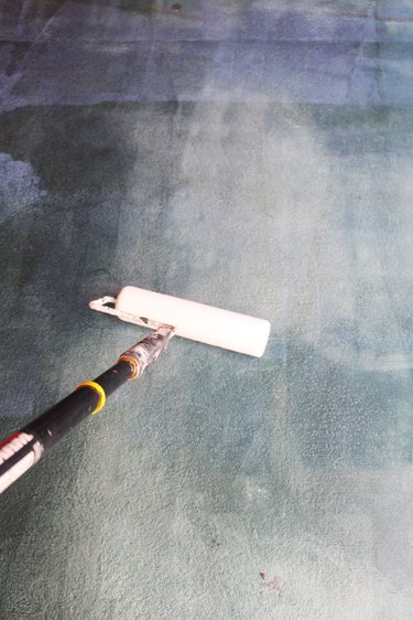 A paint roller rolling polish onto a concrete floor.