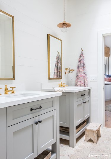 Bathroom with twin sinks featuring brass faucets and black cabinetry hardware