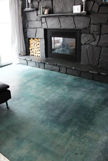 A green acid-stained concrete floor near a dark gray stone fireplace.