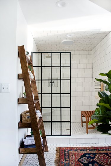 Industrial bathroom with white tile and black metal detailed glass panel